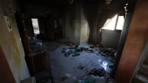 'Israeli forces took over my home and then they set it on fire' Interior image of an apartment shows graffiti on walls and burnt items and rubbish strewn on the floor.