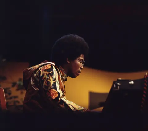 Getty Images Herbie Hancock sat at the piano, wearing glasses and a psychedelic jacket