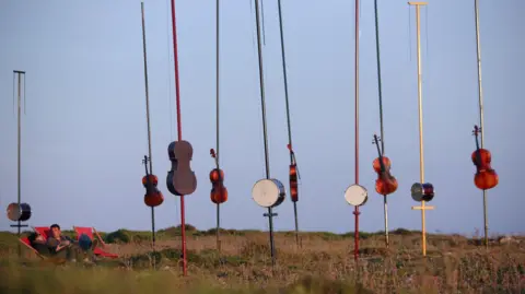 Drums and string instruments on long poles sticking into moorland