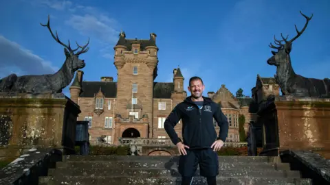 John Baikie Photography Andrew Jenkins standing on the steps in front of Ardross Castle