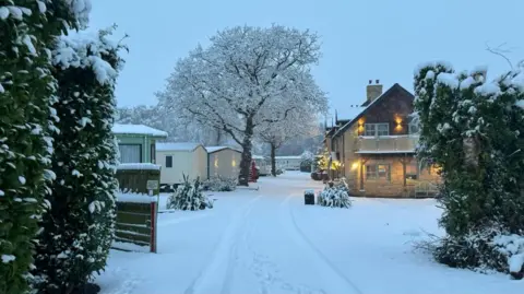 BBC Weather Watchers/Beamish holiday park Static caravans covered in snow next to a road, also covered in white with some footprints