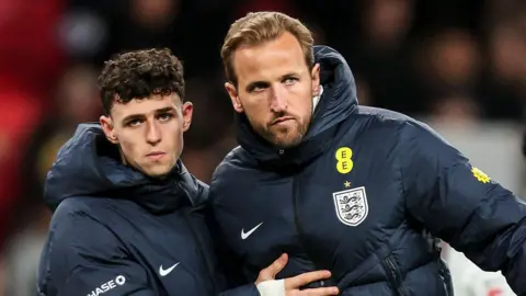 Phil Foden and Harry Kane in England blue coats after the defeat by Japan, with both players stern-faced