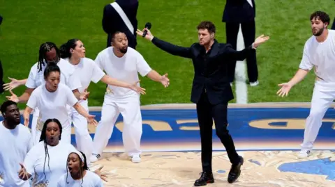 Michael Buble performing alongside other singers on the pitch