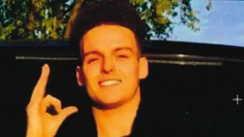 A man smiling at the camera. He is wearing all black 