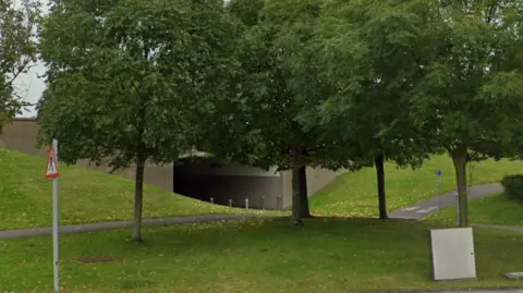 An underpass surrounded by green embankments and trees