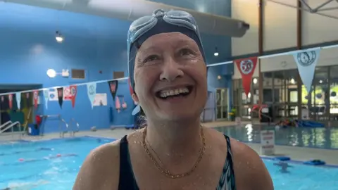 Gillian smiles by the side of a pool.