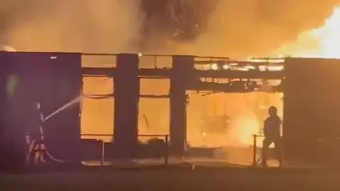 Silhouetted fire fighters spraying a burning building