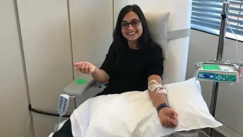Meera Shah, an asian woman, smiling while receiving cancer treatment