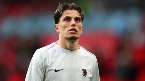 Garnacho looking up into the stands while walking out at Wembley Stadium in Chelsea's training kit