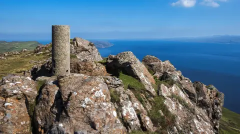 A view point at Dùn Caan, the highest hill on Raasay. The summit is rocky and provides a view over the sea. It is a beautiful sunny day.
