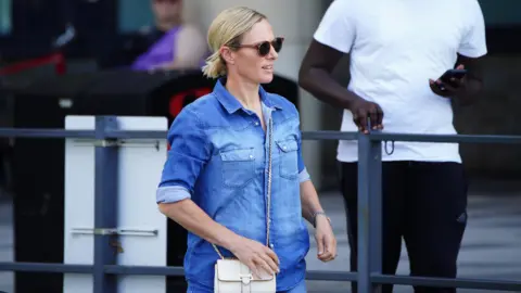PA Media Zara Phillips walks out of Southmead Hospital in Bristol in Bristol. She is wearing a blue top and shorts and carrying a white handbag