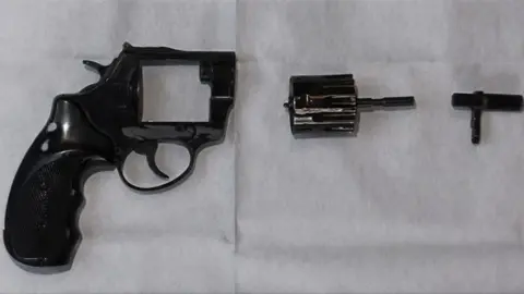 Essex Police A black revolver that has been deconstructed by the police. It's barrel is detached from the main handle and trigger.