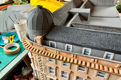 Karen Bones A cardboard model of Union Corner. It is a Victorian Building with a grey slate roof and dome.
