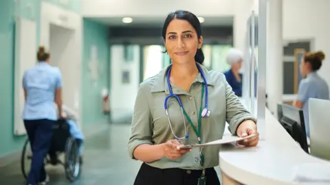 Getty Images A female doctor wearing a stethoscope standing in a hospital 
