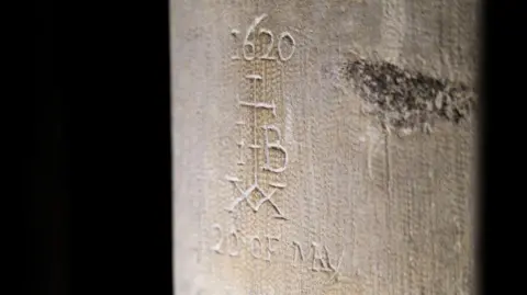 Historic graffiti showing a cross with the date '1620' above it, the letters I and B to the sides, a double xx below and the date '20 of May'.