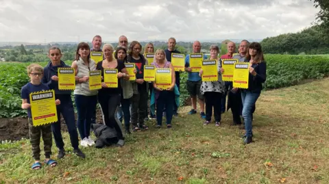 Local Democracy Reporting Service Wakefield residents stand with signs to protest a potential BESS site