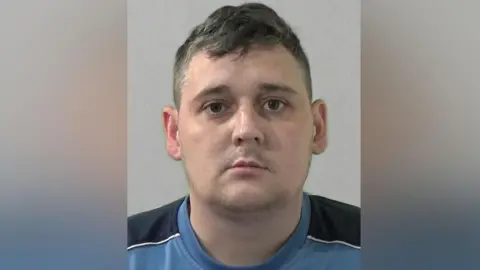 Northumbria Police David Moore Mugshot. He has a thin stubble mustache and short dark hair