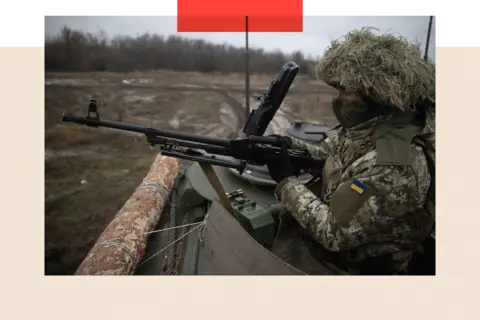 Getty Images A close-up of a Ukrainian worker  wrong  a tank, holding a firearm  astatine  the ready