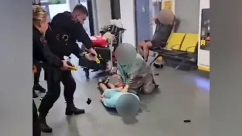 A screenshot of the video where a GMP officer kicks the man on the head at MAnchester Airport