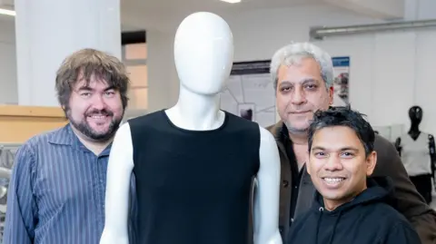 A picture of the research team standing next to a mannequin wearing a black vest