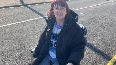 Tim Iredale/BBC Linda Cawkwell pictured outside sitting in her wheelchair. She has dark hair, glasses and is wearing a winter coat.