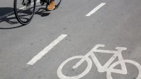 A cyclist pedalling alongside a cycle lane. 