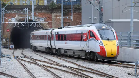 LNER Azuma train with red, white and yellow livery, emerges from a tunnel 