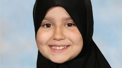 Surrey Police Sara Sharif wearing a hijab and smiling. She is looking directly at the camera. 