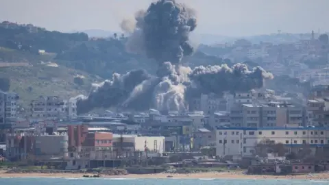 An explosion in Abbasiyeh, a neighbourhood in Tyre, Lebanon. Houses by the seaside as plumes of smoke rise