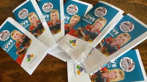 Leaflets advertising the book scheme show a a photo of Dolly Parton smiling and holding a book open. 