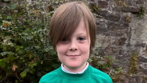 Hudson Paterson pictured wearing a green school jumper. 