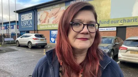 Siobhan McHaffie, a blue fleece, black glasses and red hair, stood in front of a USPCA building