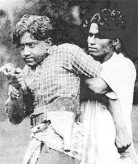 Poster of the movie Vigathakumaran A black and white poster of the film Vigathakumaran shows two men, with the man at the back forcibly clutching the other by hand.
