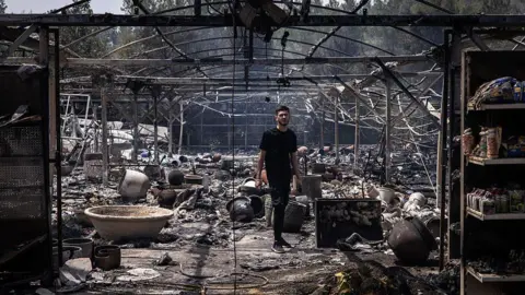 A man walks through a burnt garden shop in Mesilat Zion in central Israel