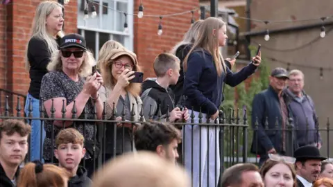 PA Media People watching the event. Some are leaning over iron railings taking pictures on their phones.