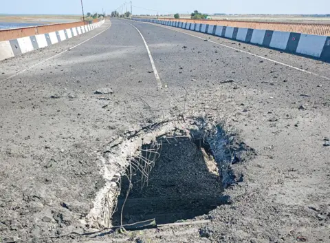 Telegram/Vladimir Saldo Blast damage to a bridge: A gaping hole can be seen in the middle of the road surface.