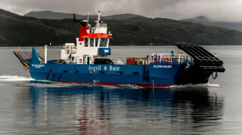 A ferry, painted blue and white, sailing through waters. A car and a van are visible on the ferry.
