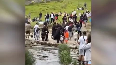 A freeze-frame from a video, which shows punches being thrown in a crowd at Dovedale