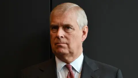 head and shoulders picture of Andrew Mounbatten-Windsor against a black background, he wears a suit and red tie, taken in Australia in 2018.