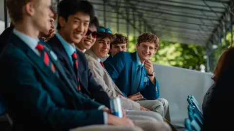 Henley Royal Regatta / Row360 A row of spectators smiling for a picture during the first day of Henley Royal Regatta 2026.