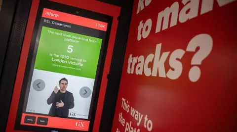 GTR A red screen with passenger information on and a man doing British Sign Language