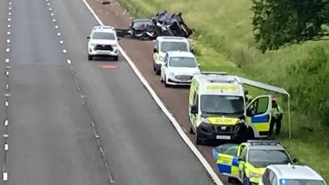 A view of a section of the M6 taken from a bridge showing the accident scene, with emergency vehicles on the hard shoulder