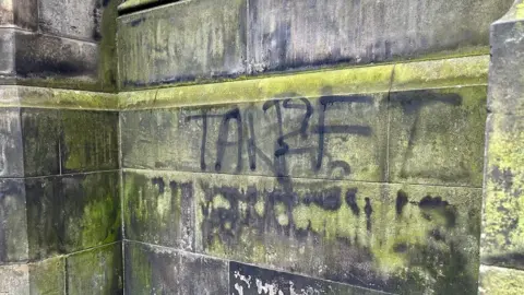 There is black graffiti on the wall of the cathedral.