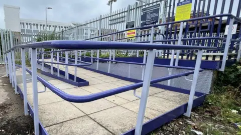 Southeastern A ramp with blue hand rails leading up to platform one at Canterbury East station