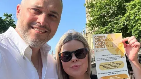 Alison Gaffney Parents Andy Hinde and Alison Gaffney are heading the Corby childhood cancer investigation. They are both standing outside next to each other. Mr Hinde is dressed in a white shirt and is looking directly at the camera and smiling. Ms Gaffney has blonde hair and is looking directly at the camera and smiling with a pair of sunglasses over her eyes.