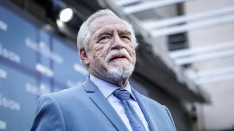 Getty Images British actor Brian Cox attends the HBO Max premiere of "Succession" at Academia de Cine on March 29, 2023 in Madrid, Spain. He wears a powder blue suit and tie and matching shirt.