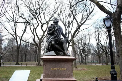Getty Images A statue of Robert Burns looking up into the sky among the trees in Central Park New York
