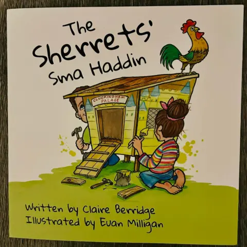 The Lois Sherret Trust A book titled 'The Sherrets' Sma Haddin' featuring a cartoon image of a chicken coop and a chicken on top of it, with a young woman kneeling down holding a paintbrush opposite a man kneeling down holding a hammer
