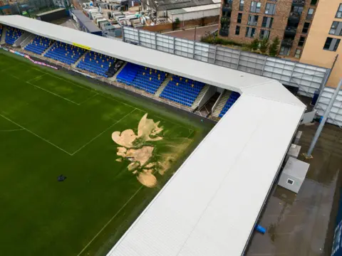 PA Media Aerial photo shows a sinkhole on the pitch and flooded walkways at the Cherry Red Records Stadium