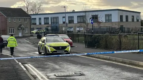 BBC Police cars and some police tape outside the primary school